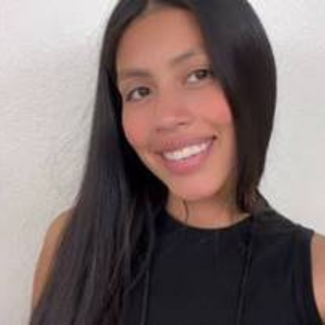 Female smiling with shoulder length black hair reaching up toward a wide brimmed hat, white blouse and jeans. The background is a bright yellow.