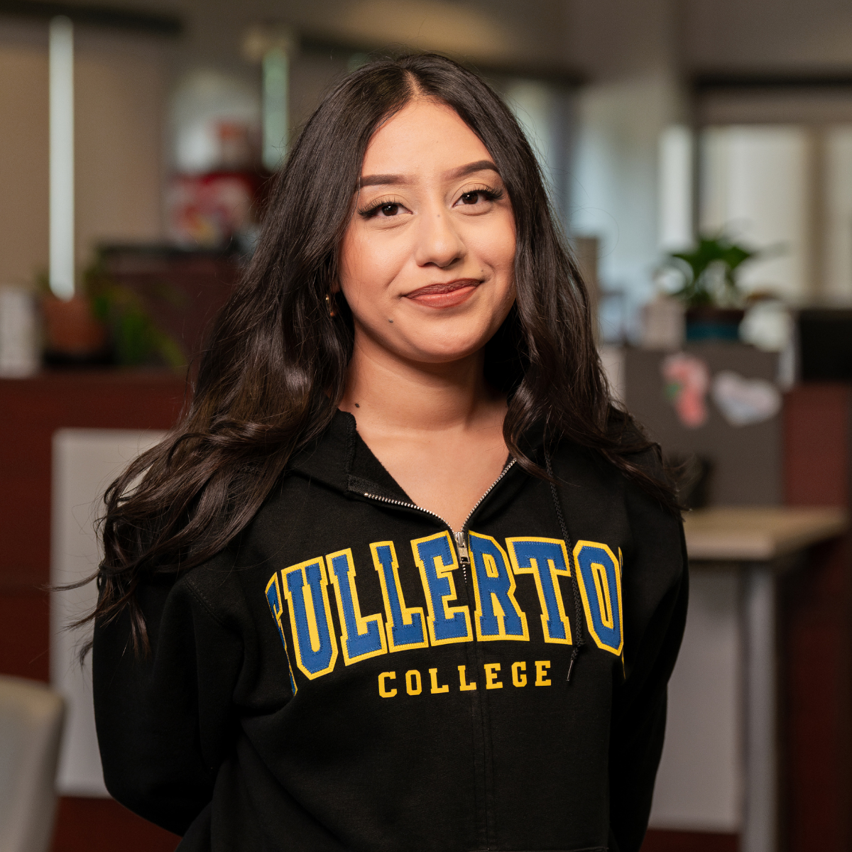 Photo of female student with a black zip up with "Fullerton College" embroidered in blue and yellow.